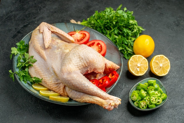 Вид спереди сырой свежей курицы внутри тарелки с зеленью и овощами на темном фоне пищевой краситель мясо курица животное