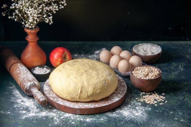 Front view raw fresh dough with eggs on a dark blue surface