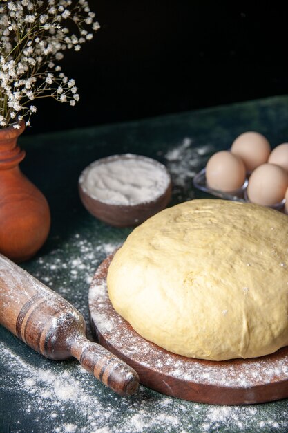 Front view raw fresh dough with eggs on dark blue surface