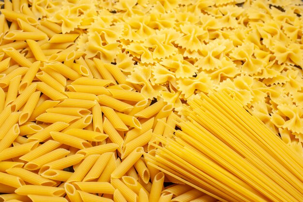 Вид спереди сырые итальянские макароны разные сформированные на светло-серой еде фото цветное тесто кухня еда