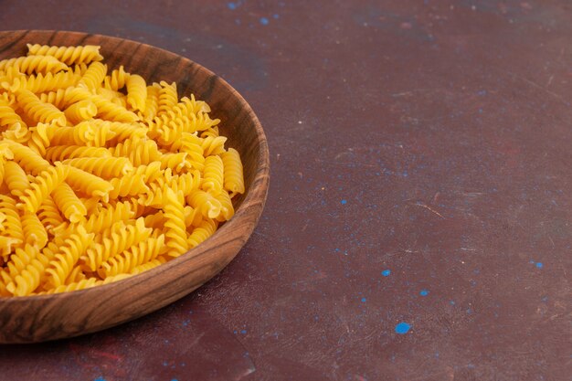 Front view raw italian pasta little formed inside plate on a dark space