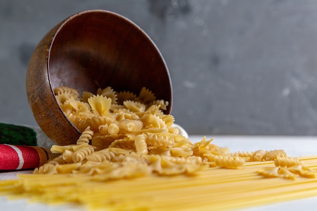 Foto gratuita una pasta italiana cruda di vista frontale lunga e piccola ciotola della pasta