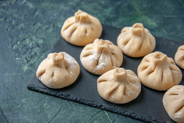 Free photo front view raw little dumplings with meat inside on dark blue surface color dish raw cooking meal dough meat flour