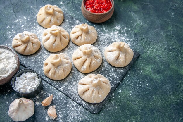 Front view raw little dumplings with meat inside on dark surface flour meat pepper color dough cooking meal cuisine dish