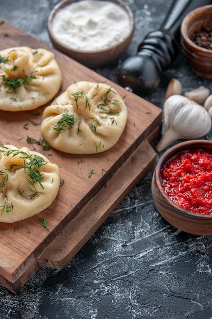 Front view of little dumplings with meat and tomato sauce on a gray surface