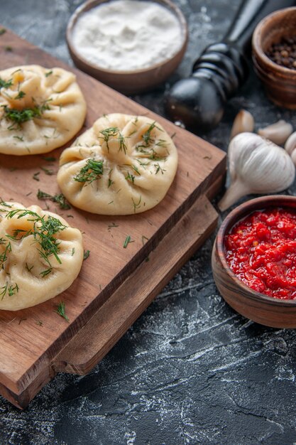 Вид спереди сырые маленькие пельмени с мясом и томатным соусом на серой поверхности мука из теста торт пирог кухня блюдо ужин приготовление мяса