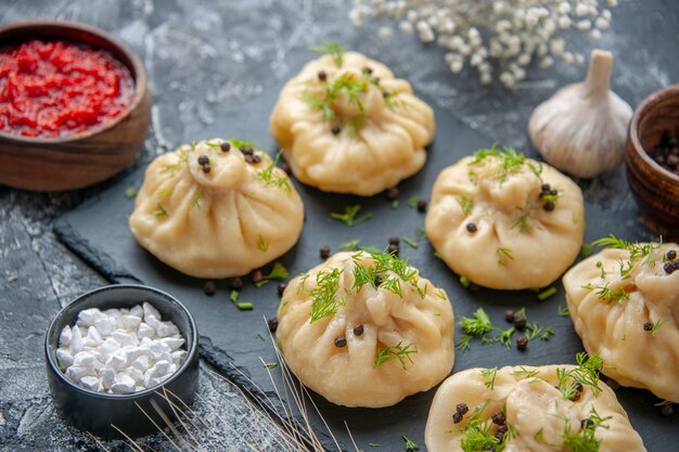 Front view raw little dumplings with tomato sauce on light-gray table meat cuisine cake dish dinner meal cooking dough