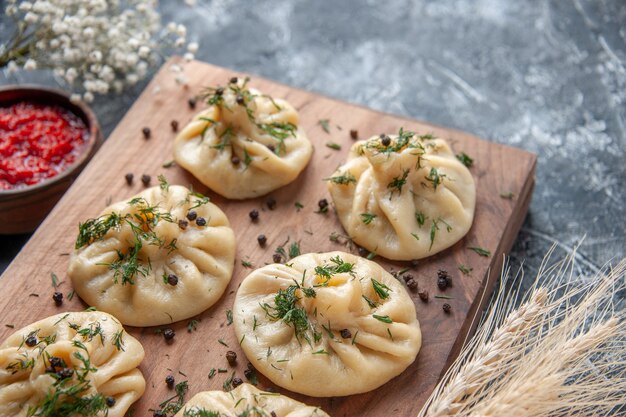 Front view raw little dumplings with tomato sauce and seasonings on gray surface dish meat dough cake cooking cuisine dinner meal