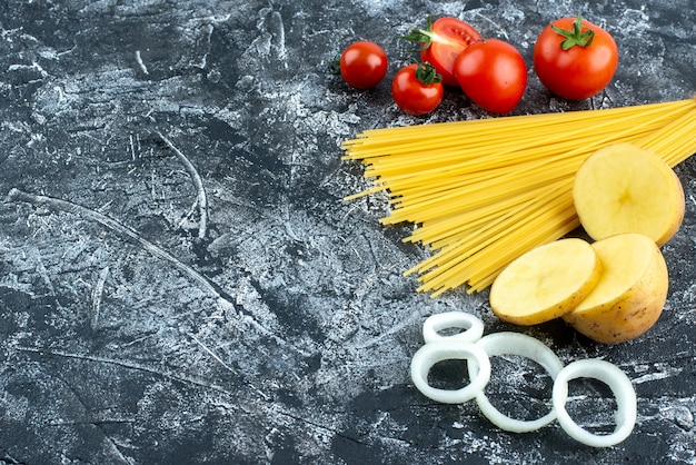 Вид спереди сырые длинные макароны с красными помидорами на сером фоне приготовление цветного салата кухня овощная кухня еда