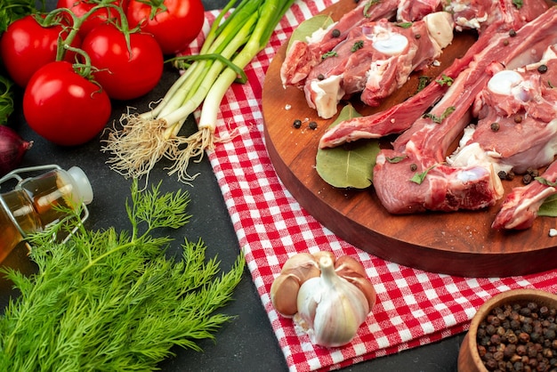 Front view raw meat slices with fresh vegetables and greens on dark background butcher meal food dinner dish salad ripe meat