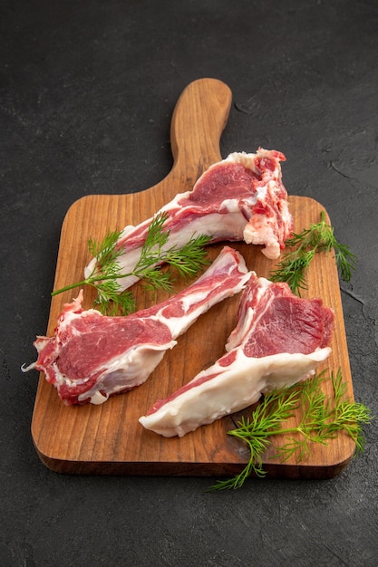 Front view raw meat slices with greens on dark-gray background cow color meat photo raw animal pepper chicken
