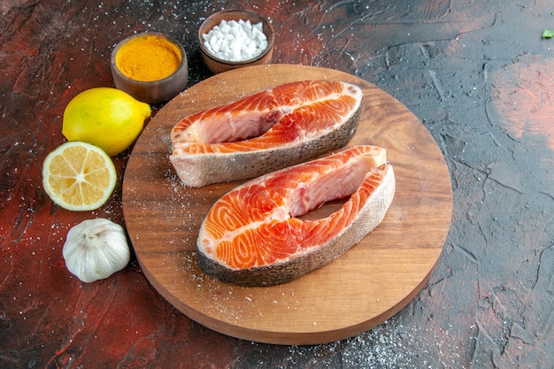 暗い背景に調味料とレモンを添えた生肉スライスの正面図リブフードミール動物料理肉