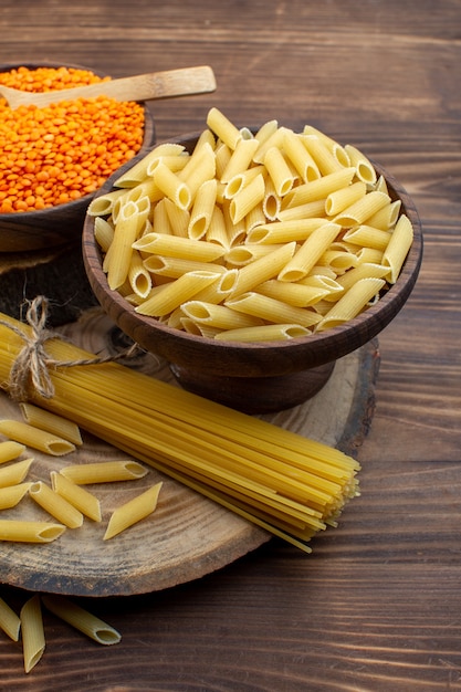 Front view raw pasta with orange lentils on brown surface