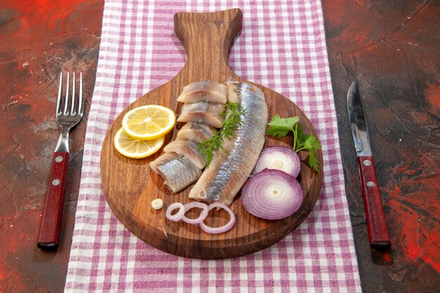 Вид спереди сырая нарезанная рыба с луковыми кольцами и лимоном на темной еде, салат из морепродуктов, мясная закуска, здоровье