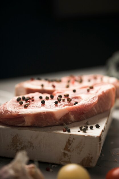 Front view raw steak on wooden board with ingredients