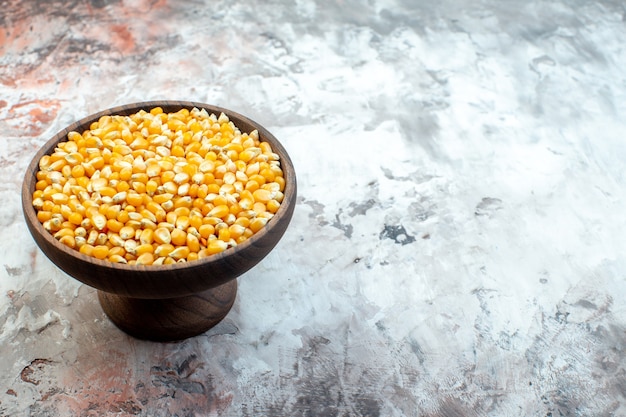 Front view raw yellow corns inside plate on light surface