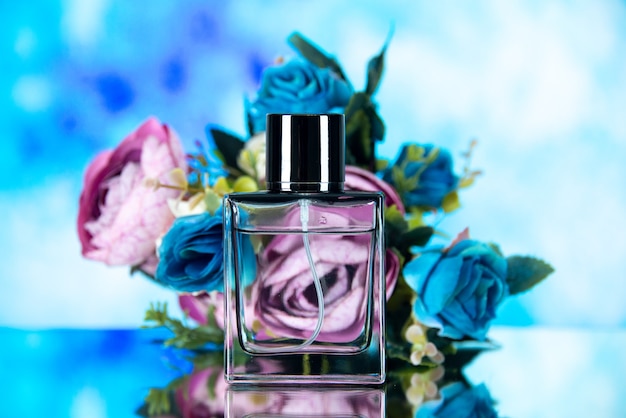 Vista frontale dei fiori colorati della bottiglia di profumo rettangolari su azzurro sfocato Foto Gratuite