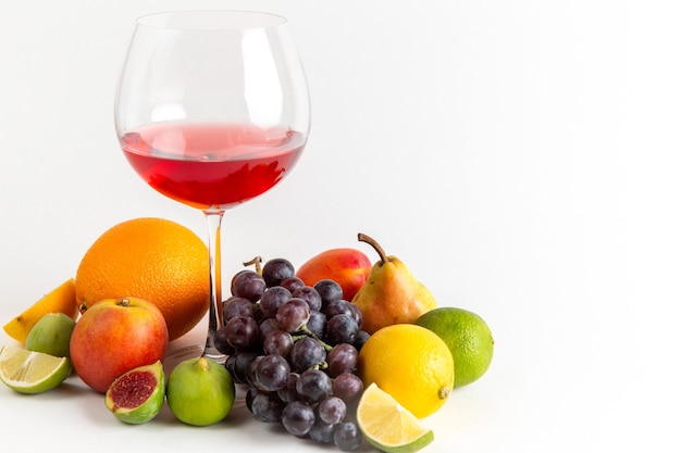 Бесплатное фото Вид спереди красный алкогольный напиток внутри стакана с разными свежими фруктами на белой стене алкогольный напиток ликер виски-бар