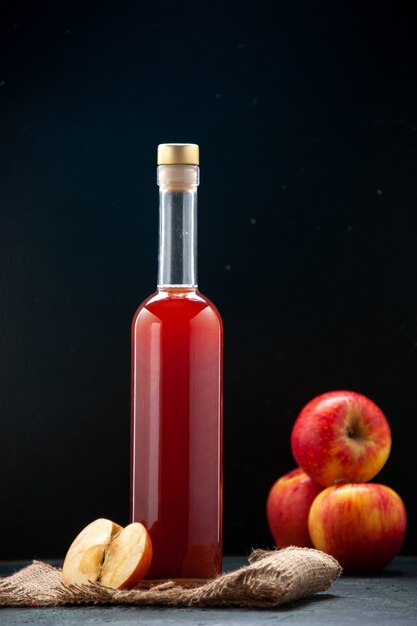 Front view red apple sauce in bottle with fresh apples on a dark surface