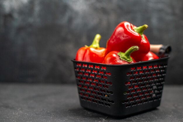 Front view red bell-peppers spicy vegetables on a dark background