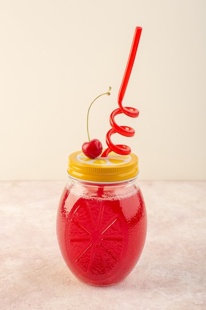 Красный вишневый коктейль с соломкой на розовом столе, вид спереди, свежий фруктовый напиток
