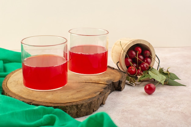 a front view red cherry juice with fresh cherries on the pink desk color fruit cocktail drink