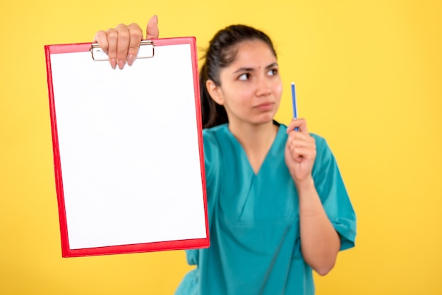 Front view of red clipboard in female hand on yellow isolated wall