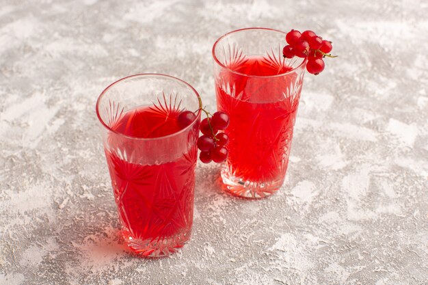 Front view red cranberry juice inside long glasses on bright desk