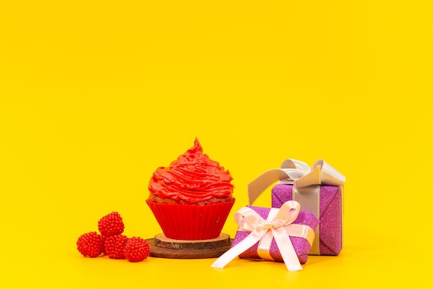 新鮮な赤いラズベリーと黄色の机の上の紫色のギフトボックスと正面の赤いフルーツケーキ