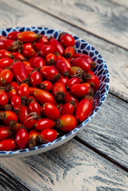 Вид спереди красные плоды спелых и кислых ягод на серой поверхности плодовых ягод цвета витаминного дерева