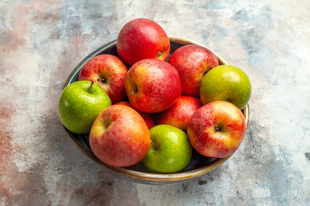 Front view red and green apples in bowl on nude background