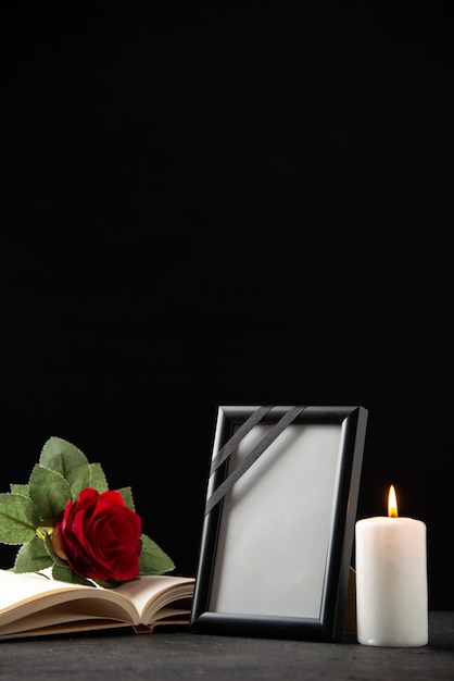 Front view of red rose with book and picture frame on black