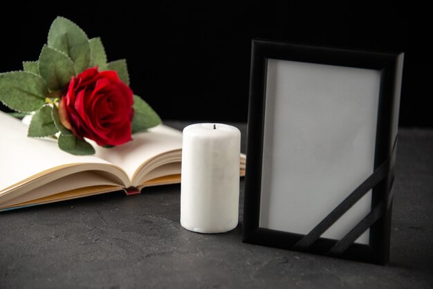Front view of red rose with book and picture frame on black
