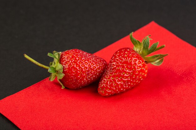 A front view red strawberries isolated mellow juicy on the red and black background berry textured