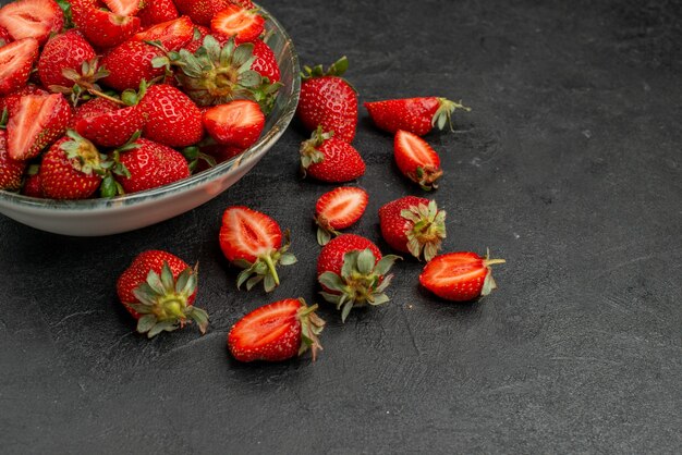 Front view red strawberries sliced and whole fruits on a grey background summer color wild tree  juice berry