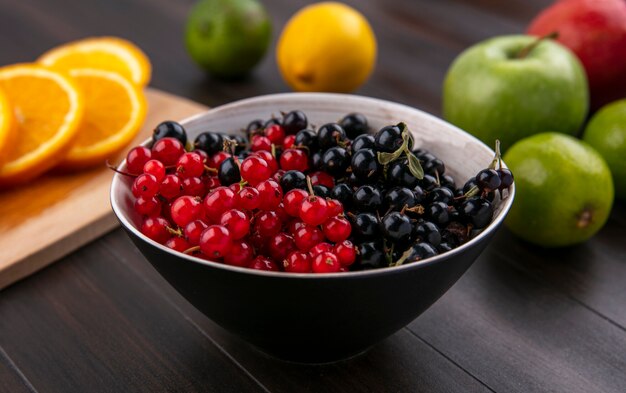 Front view of red with black currant with apples on a wooden surface