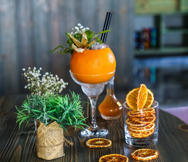 Вид спереди освежающий коктейль в апельсине с декором цветами и сушеными апельсиновыми дольками