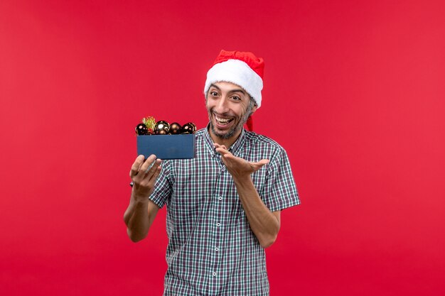 Front view of regular male with christmas tree toys on red