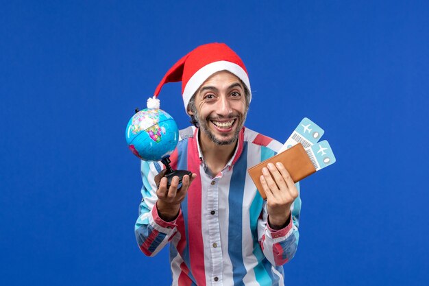 Вид спереди обычного мужчины с глобусом и билетами на синий пол эмоции праздник новый год