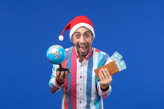 Front view regular male with globe and tickets on a blue wall emotions holiday new year