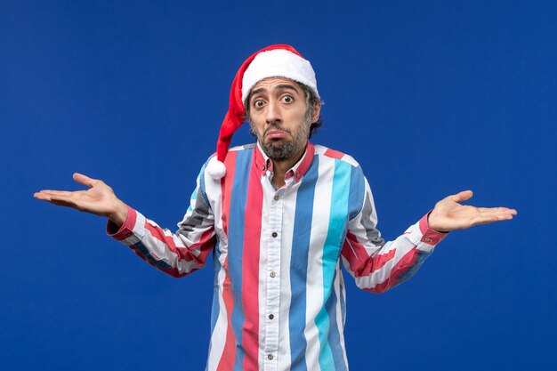 Front view regular male with red christmas cap on blue desk santa holiday christmas