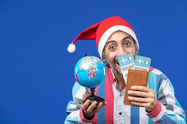 Front view regular male with tickets and globe on blue wall color holiday new year