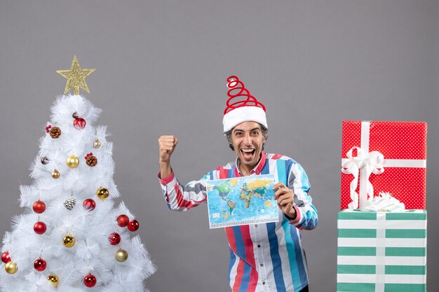 Front view rejoiced man with spiral spring santa hat holding world map