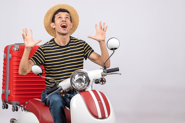 Front view of rejoiced young man with straw hat on moped