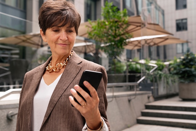 Front view rich woman holding smartphone