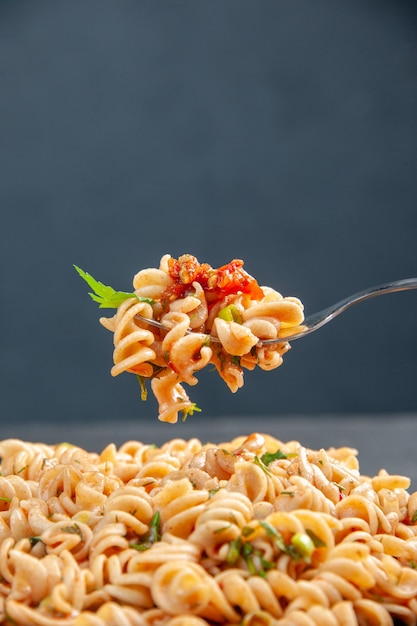 Front view rotini pasta on fork on dark isolated surface free space food photo