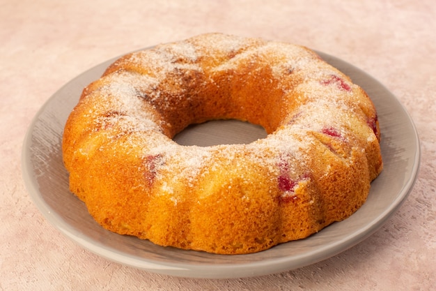 A front view round cherry cake inside plate on the pink desk