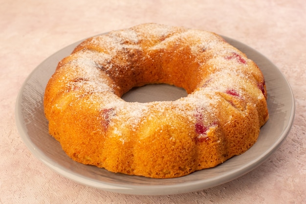 Круглый вишневый торт, вид спереди, внутри тарелки на розовом столе