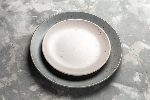 Вид спереди круглая пустая тарелка серого цвета с белой тарелкой на сером столе.