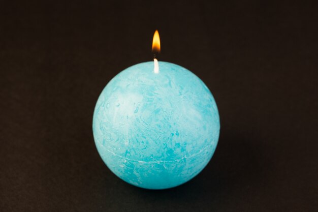 전면보기 둥근 모양의 촛불 조명 파란색은 어두운 배경에 밝은 불 장식으로 설계되었습니다.